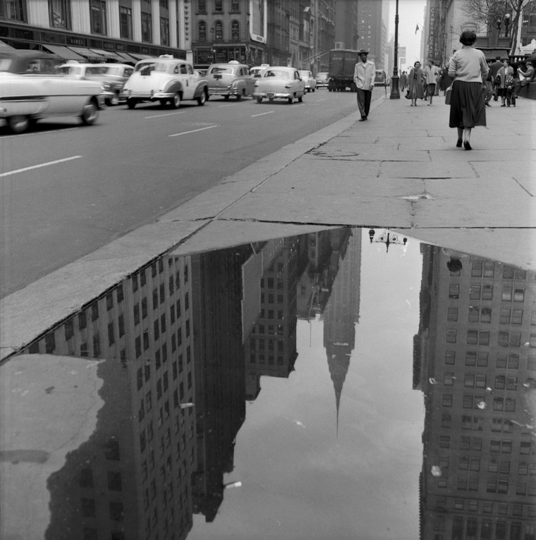 The reflection of the Chrysler Building is seen in a puddle on a sidewalk along 42nd Street in New York in April of 1954.